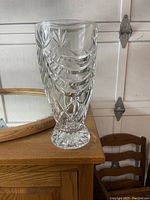Clear heavy glass vase with etched floral and geometric designs, no chips visible, shown on wooden surface.