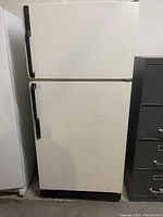 Closed front view of white Kenmore refrigerator with freezer on top and fridge below