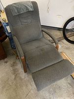 Light blue La-Z-Boy recliner chair fully extended showing stained fabric upholstery, padded armrests with wooden elements, and reclined position.