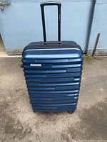 Large dark blue Samsonite hard shell suitcase standing upright showing telescoping handle extended and four spinner wheels visible