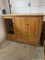 Front view of oak media console with three doors and four drawers.