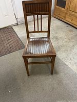 Front view of antique wooden chair showing vertical slat backrest and seat