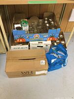 Overall view of assorted canning jars in cardboard boxes beneath workbench