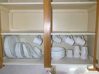 Full cupboard view showing plates on left and mugs hanging on right