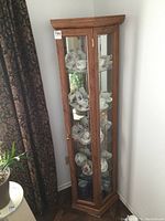 Front view of corner curio cabinet showing glass shelves and interior contents