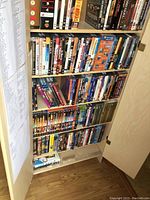 Cabinet with five shelves filled primarily with DVDs and a few VHS tapes visible on bottom shelf