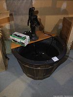 Full view of outdoor barrel tub with attached metal hand pump and electric pump inside.