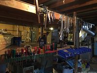 Wide view showing hand tools organized in a workshop setting: screwdrivers, wrenches, ratchets, levels, with hanging combination wrenches