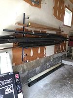 Multiple black ABS pipes hanging on wall-mounted rack