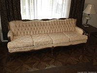 Full frontal image of the vintage sofa showing four seat cushions, tufted backrest, and carved wood frame detail.