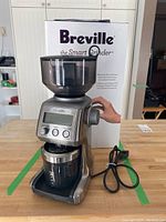 Full view of stainless steel grinder with original packaging behind