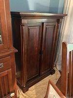 Front view of wooden cabinet with closed sliding doors and decorative side columns.