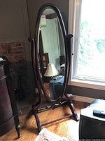 Front view of the tall oval cheval mirror showing wood veneer frame and metal detail.