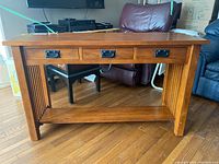 Front view showing three drawers with black metal handles, bottom shelf, and slatted sides.