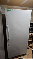 Full frontal view of the white upright freezer showing door and handle