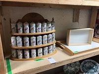 Wide shot of three-tier spice carousel with 24 jars on left and wooden bed tray on right