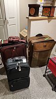 Photo showing five pieces of luggage stacked and arranged with a large brown Jaguar suitcase to the right.