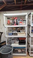 Full view of plastic utility shelf with assorted hardware, tools, and supplies on shelves