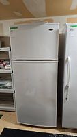 Full view of white Amana top-mount refrigerator with freezer compartment on top