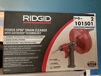 Box front showing the product name Ridgid Power Spin Drain Cleaner with Autofeed Technology, features listed in English, French, and Spanish, condition sticker and lot number label visible.