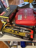 Ryobi cordless angle grinder box, Craftsman stapler case, Stanley FatMax air ratchet wrench box on display.