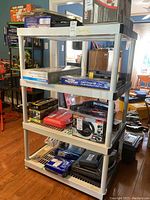 Utility shelving displaying assorted tools and hardware on shelves in a home interior with wooden floor and furniture.