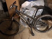 Side view of entire black Kona Lanai mountain bike leaning against storage items