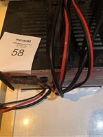 Front and top view of the Motomaster battery charger showing controls, display meter, and attached cables.