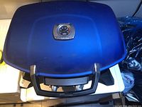 Closed view of the portable BBQ showing navy blue lid and black handle.