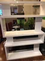 Front view of the white lacquered bookcase showing multiple shelves and vertical dividers.