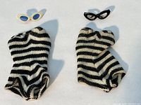 Two striped bathing suits side by side with both pairs of sunglasses above them