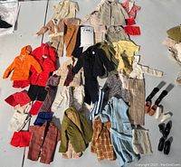 Full collection of vintage Ken and Allan doll clothing laid out on table including various jackets, pants, shirts, and shoes.