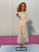 Front view of the full doll standing on the display stand, showing dress and posture.