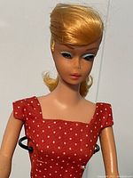 Close-up of doll head showing blond swirl ponytail hair and facial features, note rough spot on nose
