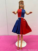 Full front view of dressed Barbie doll on stand