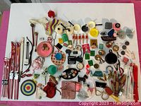 Overhead photo showing a wide assortment of vintage Barbie and Ken accessories including skis, fishing poles, toy cups, and various small items.