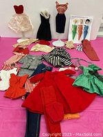 First photo shows fifteen distinct Barbie outfits on mannequin stands and laid flat, including formal gowns, coats, and tops.