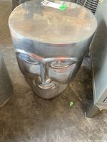 Front view of the metal face accent table displaying facial features and reflective metal surface.