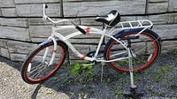 Side view of white Kronenbourg bicycle showing red rims, fenders and rear rack