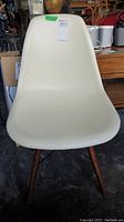 Front view of a white plastic chair with wooden legs showing the curved seating area.
