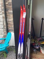 Full view of Madshus skis leaning against wall, showing overall length and color design.