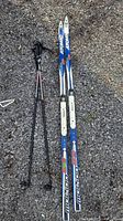 Full view of Atomic Motion 52 skis with attached bindings and Alpina poles on gravel surface