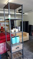 Full view of five-tier shelving unit showing metal frame, wood shelves, and single drawer