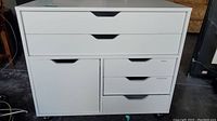 Front view of the white dresser showing two large drawers, a cabinet door, and three smaller drawers with recessed handles.