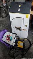 Boxed SKLZ pop-up golf net with a person pictured swinging a golf club, yellow and black Airhead inflator, and a colorful tote bag
