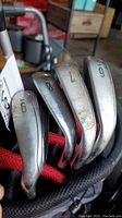 Chrome-finished Callaway irons labeled 6, 7, 8, 9 and PW seated in red/black stand bag