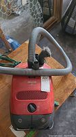 Red Miele S2 Air Clean vacuum with hose attached and visible control dial.