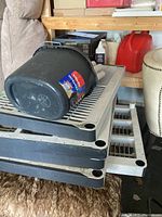 Five gray plastic shelving panels stacked with black plastic bucket on top.