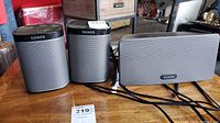 Three Sonos speakers arranged side by side (two Play:1 and one Play:3) showing front grilles and cables