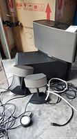 Overall view: Sonos Play:5 front, black rectangular box behind, two small satellite speakers on stands, cables on floor